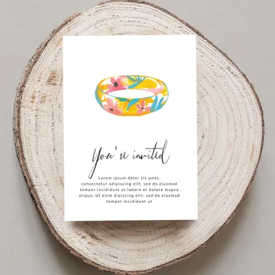 Floral ring invitation on wood slice with "You're invited" text.