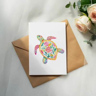 White card featuring a colorful floral sea turtle, on a brown envelope.