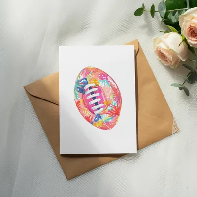 Watercolor rugby ball with floral pattern on card over envelope, with roses.