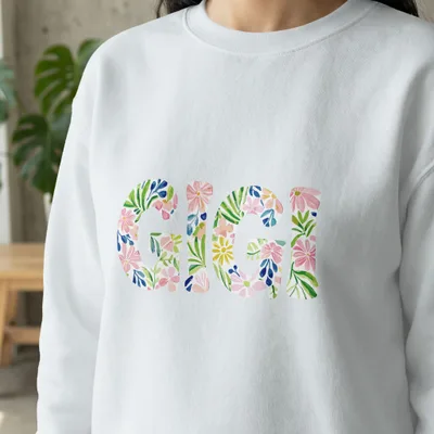 White sweatshirt with "Gigi" in floral watercolor letters.