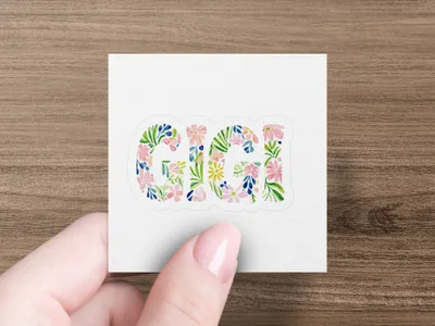 Gigi text in floral watercolor pattern on sticker held by a thumb.