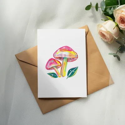 Illustration of colorful mushrooms and leaves on a white card atop an envelope.