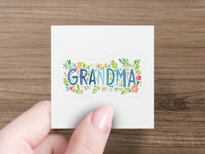 Floral "Grandma" text on a white sticker held by a hand.