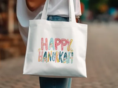 White tote bag with colorful "Happy Hanukkah" text and floral accents.