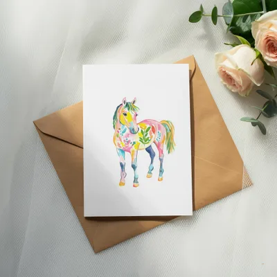 Colorful watercolor horse illustration on a card atop a brown envelope.