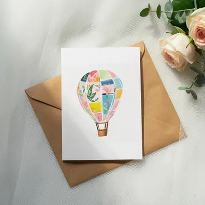 Card with colorful patchwork hot air balloon illustration on brown envelope.