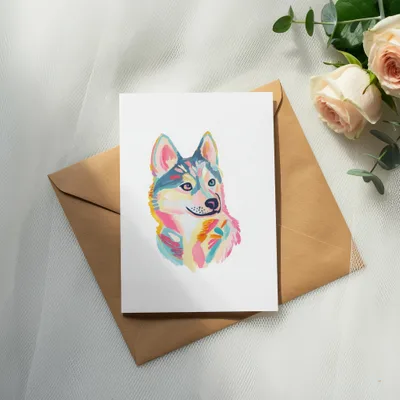 Watercolor husky portrait on white card atop brown envelope with roses.