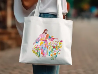 Jesus with open arms surrounded by colorful flowers on a white tote bag.