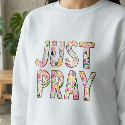 White sweatshirt with "JUST PRAY" in floral watercolor lettering.