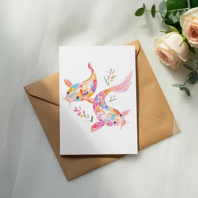 Two colorful koi fish illustration on a card resting on an envelope.