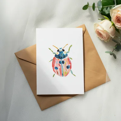 Hand-painted ladybug illustration on a card with a kraft envelope and roses.