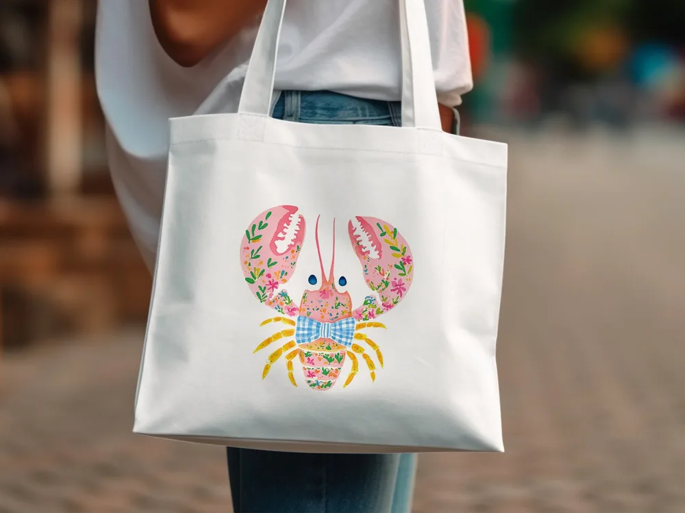 White canvas tote bag with a pink floral lobster graphic and blue plaid bow.