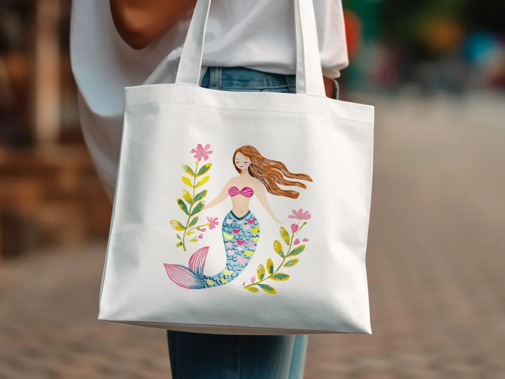 Tote bag with watercolor illustration of a mermaid surrounded by floral accents.