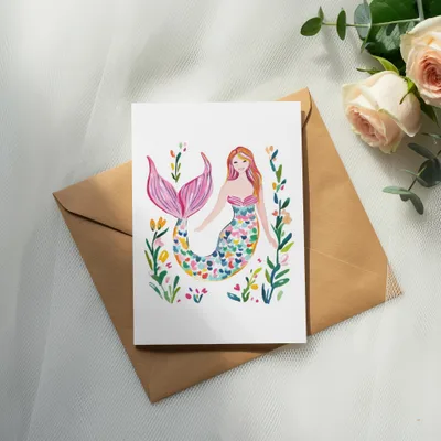 Watercolor mermaid illustration with floral accents on an open envelope.