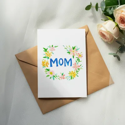 Card with "MOM" in colorful watercolor flowers on a brown envelope.