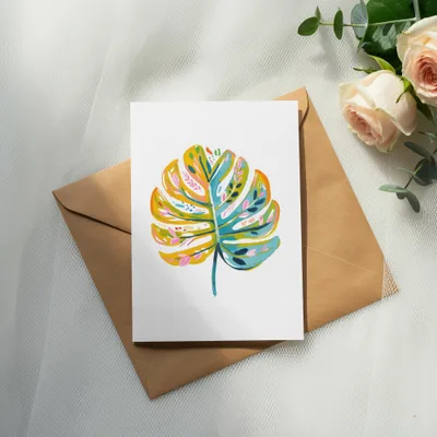 Card with colorful monstera leaf illustration on a brown envelope with roses.