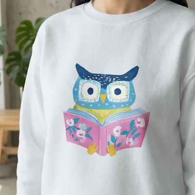 White sweatshirt with cartoon owl reading a pink book.