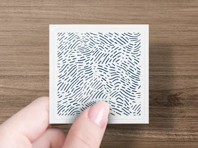 Hand holding a small square card with a blue wavy line pattern.
