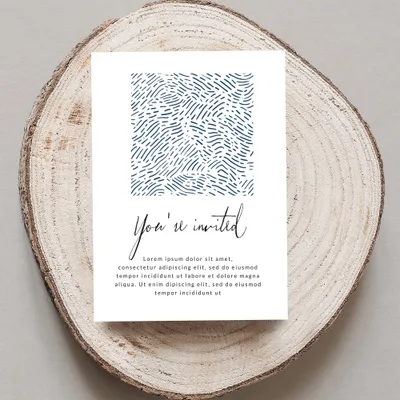 Invitation card with "You're invited" text and abstract blue pattern on wood slice.