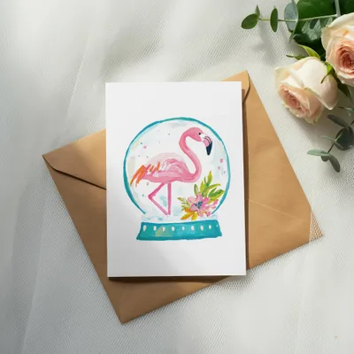 Card with a pink flamingo inside a snow globe and floral accents.