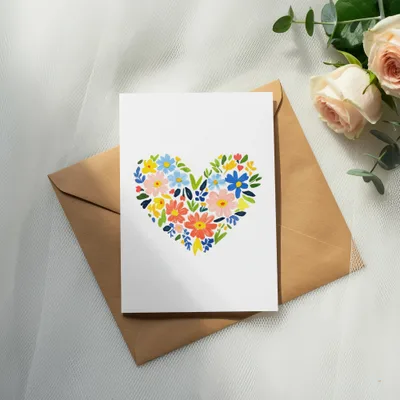 Blank greeting card with a floral heart design sits on an envelope.