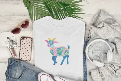 White t-shirt with a colorful patterned goat graphic, laid flat with accessories.