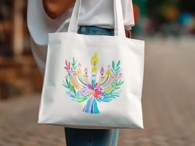 White tote bag with a colorful watercolor menorah illustration.