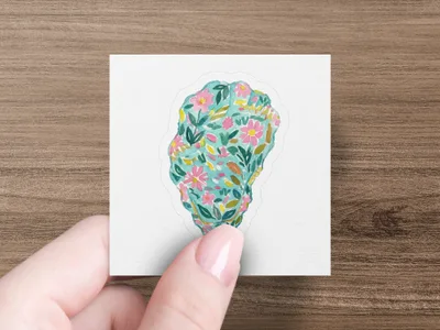 Hand holding a sticker with a floral pattern of pink flowers and green leaves.
