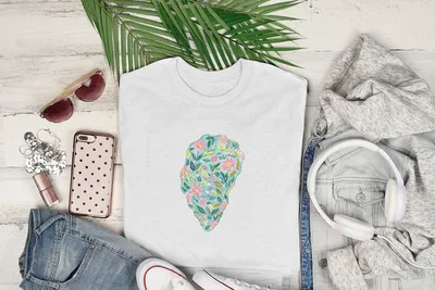 White t-shirt with a colorful floral pattern overlay, laid flat with accessories.