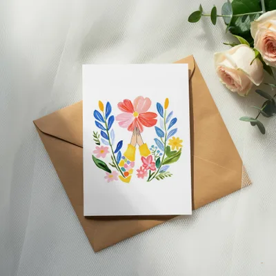 Card with colorful flowers and praying hands on brown envelope.