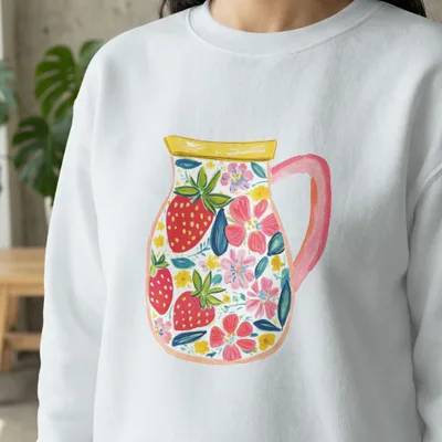 White sweatshirt featuring a colorful painted pitcher filled with strawberries and flowers.