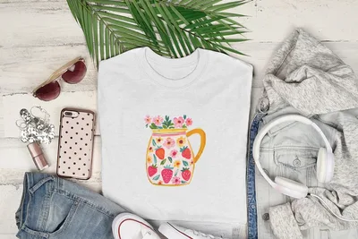White t-shirt with a floral and strawberry pitcher graphic, styled with jeans, headphones, and sunglasses.
