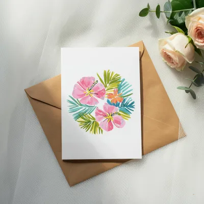 Card with pink hibiscus flowers and green leaves on brown envelope.