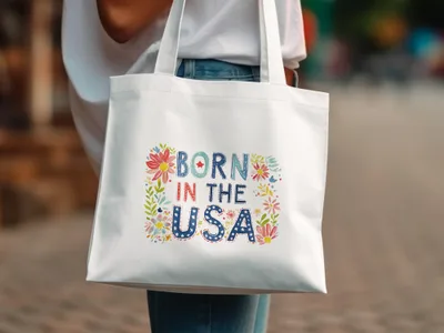 White tote bag with "Born in the USA" text and floral accents.