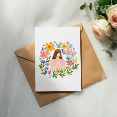 Greeting card with floral wreath and praying hands, on a brown envelope.