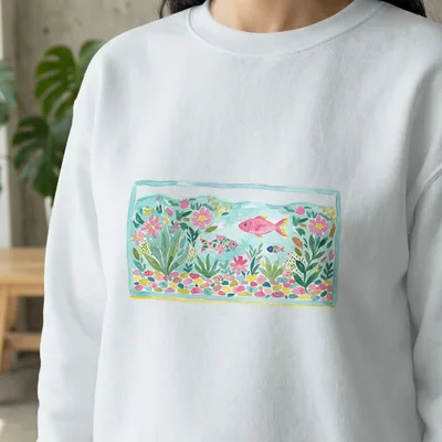 White sweatshirt with watercolor illustration of a fish tank with pink and blue fish.