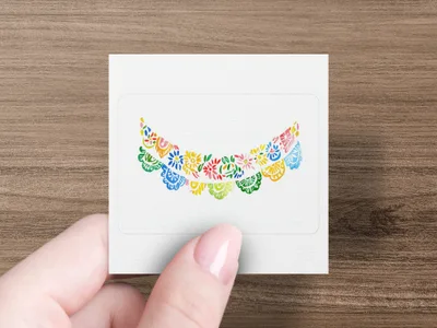Hand holding square sticker with colorful floral garland design.