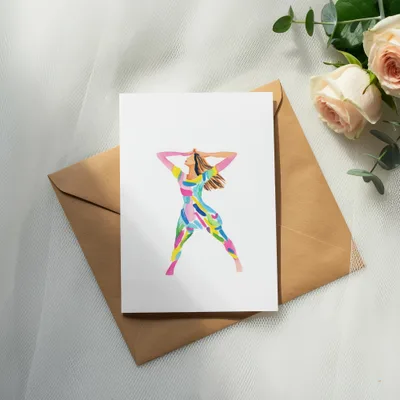 Card with colorful abstract figure on brown envelope with roses and eucalyptus.