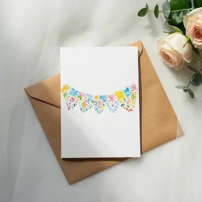 White card with colorful floral garland design on brown envelope.
