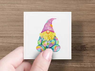 Watercolor gnome with colorful patterned hat and clothing, held by a hand.