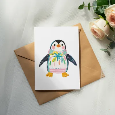 Card featuring a watercolor penguin with a floral collar, on a brown envelope.