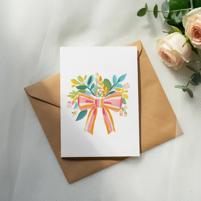 Card with a watercolor floral bouquet and pink bow on a brown envelope.