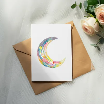 Watercolor crescent moon illustration on card with roses and envelope.