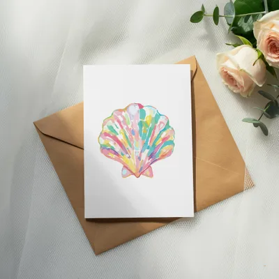 Watercolor seashell illustration on white card with brown envelope and roses.