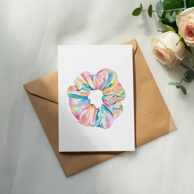 Watercolor illustration of a colorful scrunchie on a white card.