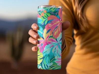 Person holding a tall tumbler with a vibrant floral pattern.