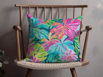 Pillow with a vibrant tropical floral pattern on a wooden chair.
