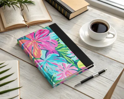 Floral patterned journal with pen and coffee cup on a desk.