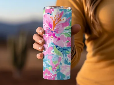 Floral patterned tumbler held by hand with blurred background.