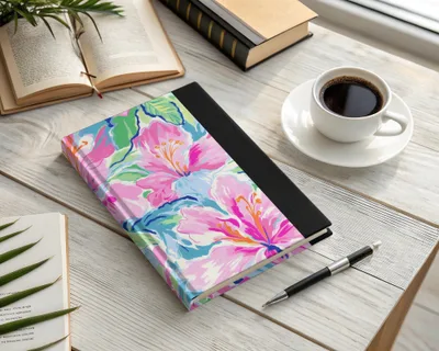 Floral patterned notebook with pen and coffee on a wooden desk.